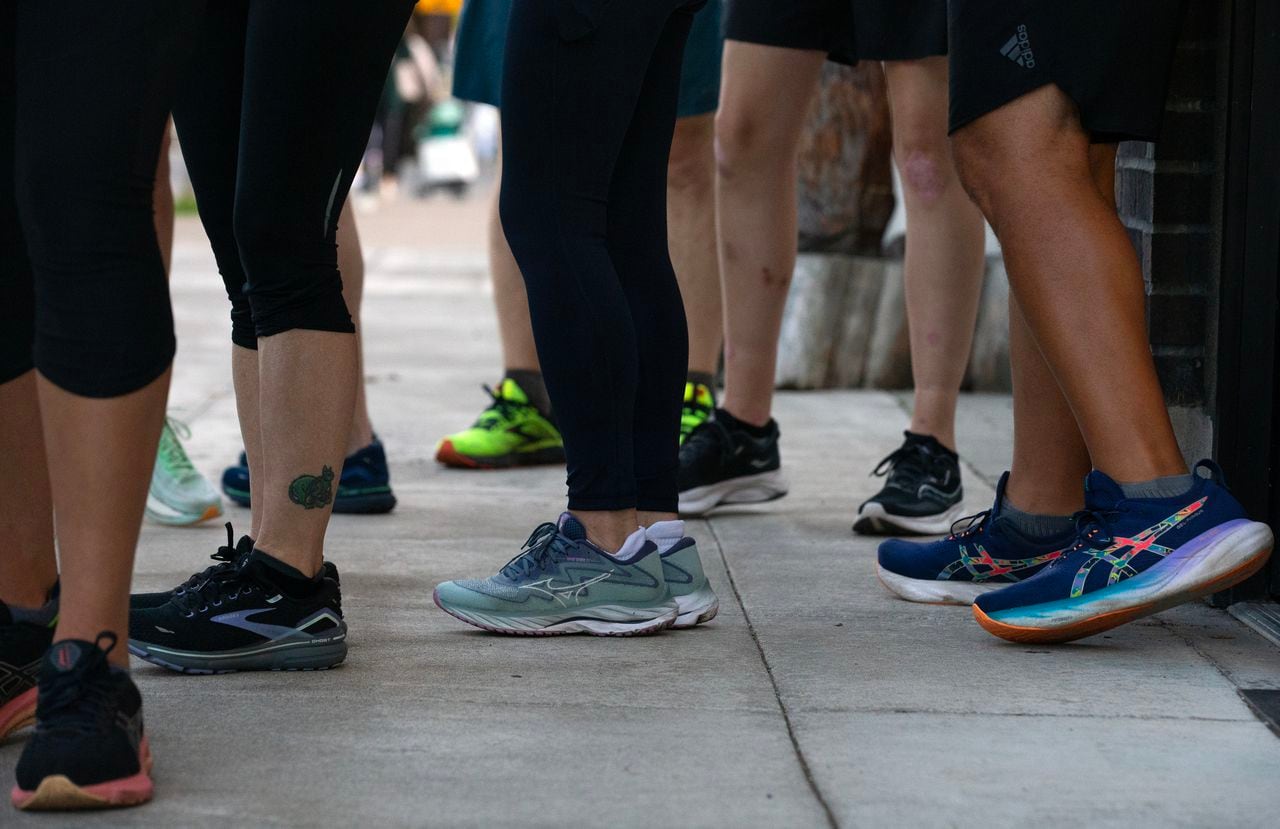 A group of people's legs, each wearing colorful running shoes