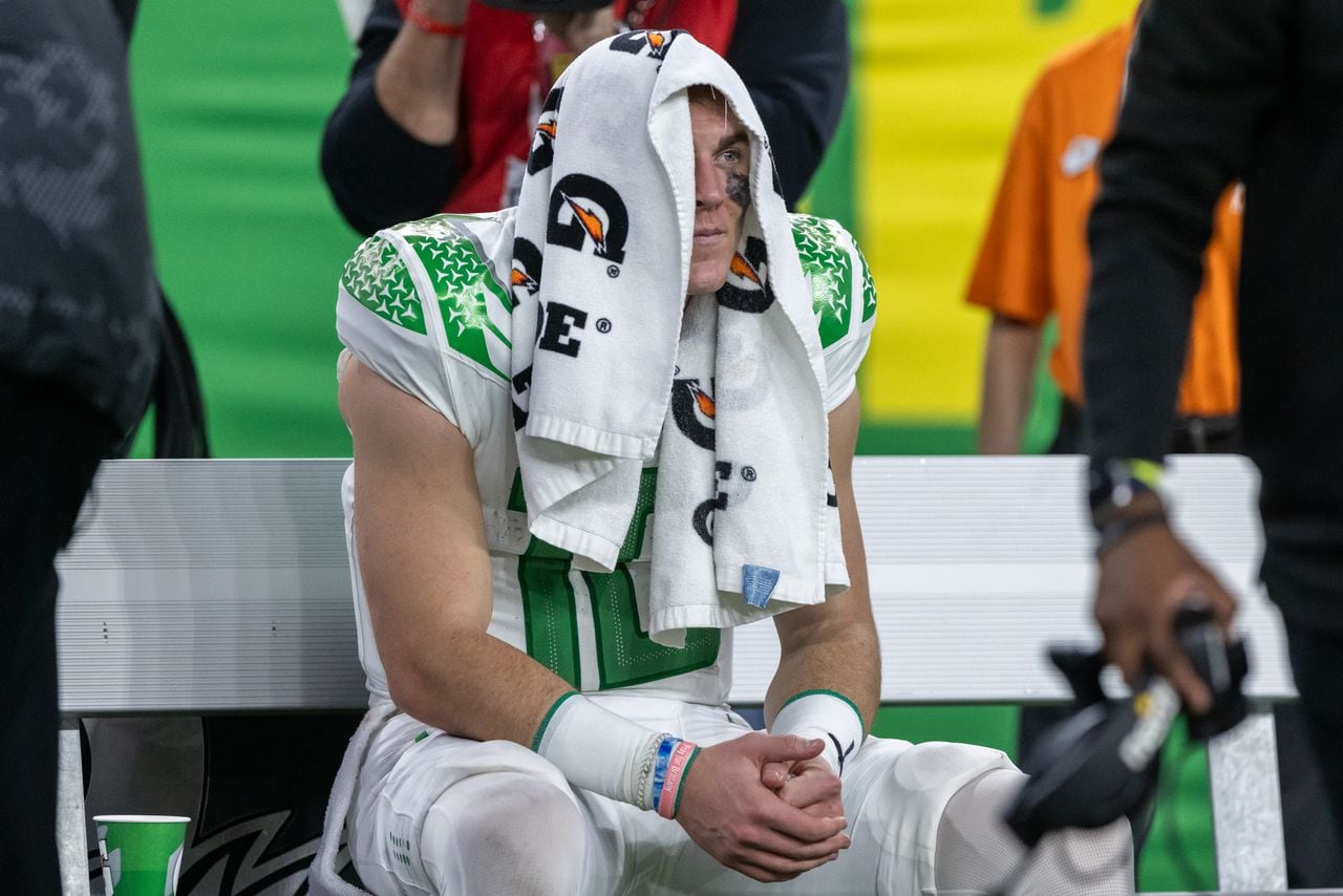 Oregon quarterback Bo Nix sits on the bench with a towel over his head