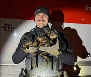 An Oregon State Police trooper poses with four of the 15 dogs rescued from a U-Haul trailer on Nov. 23, 2023, in Klamath Falls.