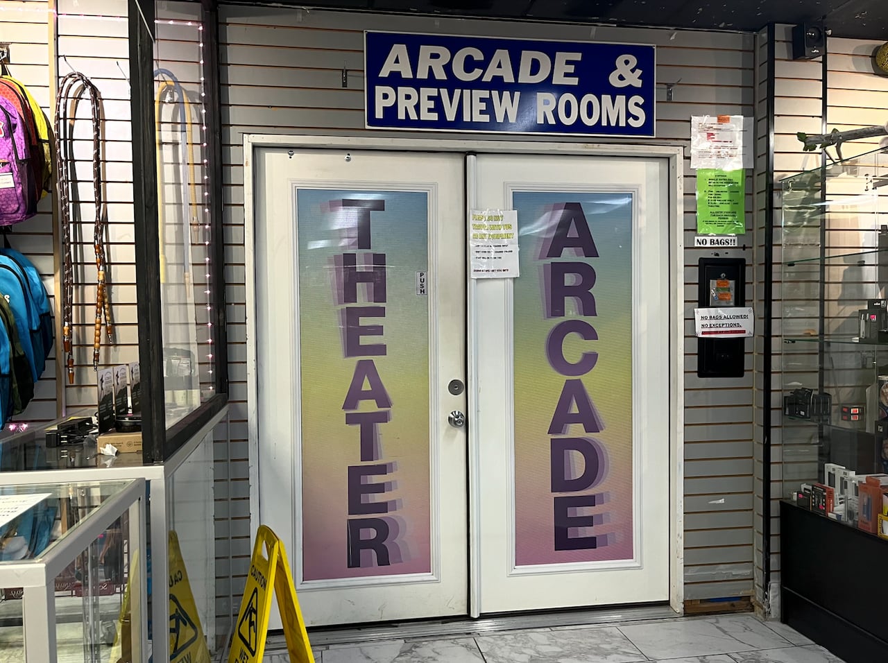 A photo of a store interior with a set of double doors that say "Theater" and "Arcade." A sign above the doors says "Arcade & preview rooms."